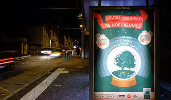 Photographie de nuit d'une affiche abribus  illuminée pour les fêtes de Noël. L'affiche représente une boule à neige avec un arbre à l'intérieur