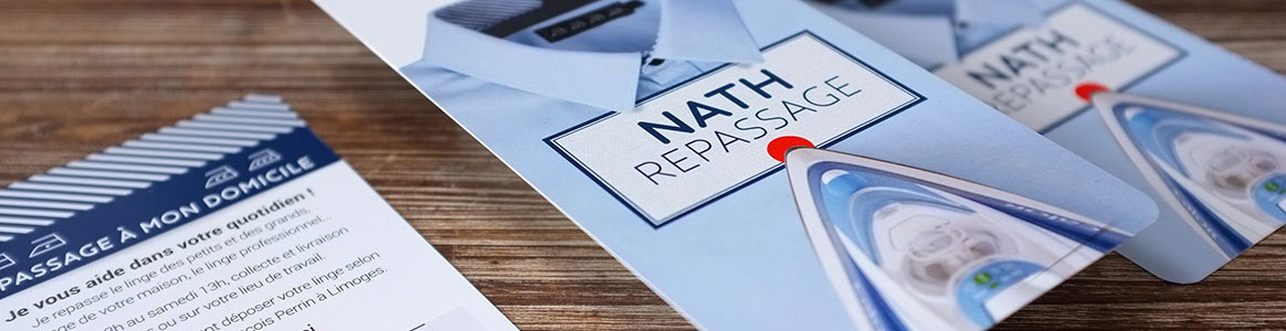 Photographie des flyers Nath repassage sur une table en bois.